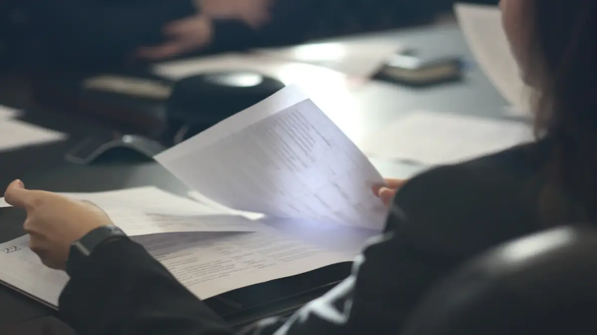 a woman sitting at a table reading a paper