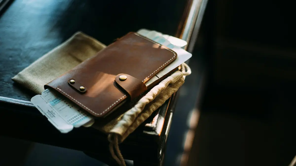 brown leather long wallet on brown wooden chair