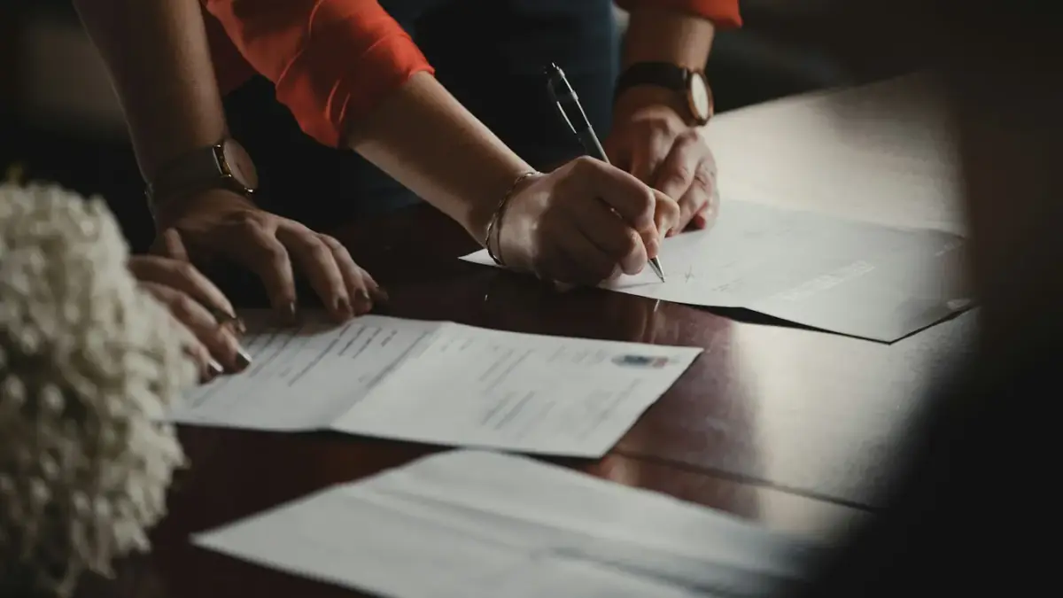 person in orange long sleeve shirt writing on white paper