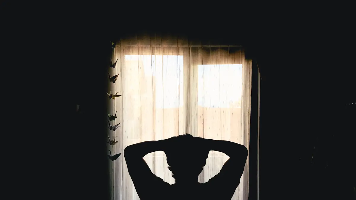 Silhouette of a person with hands behind head