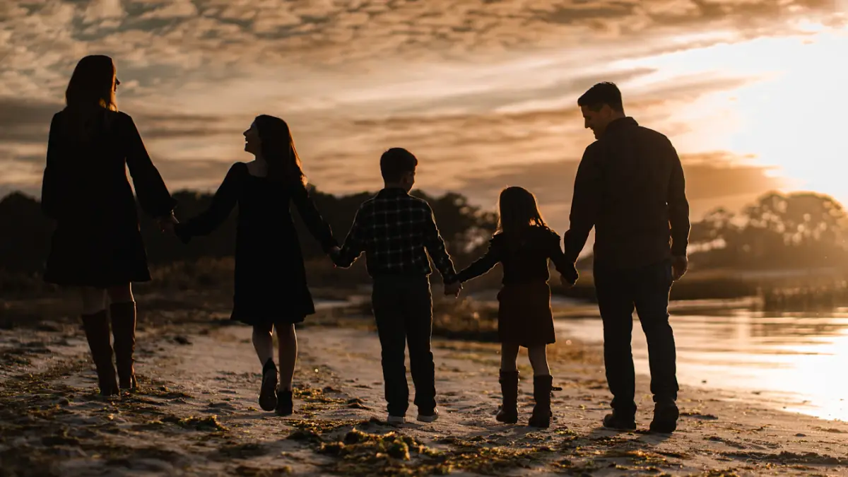 a family walking on the beach at sunset