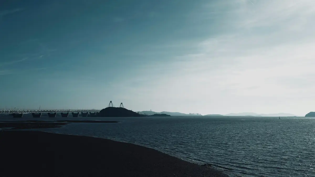a large body of water with a bridge in the background