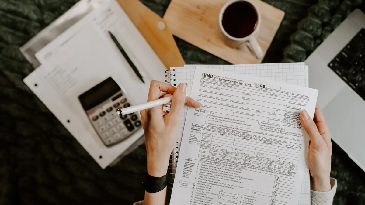 Person reviewing documents with calculator and laptop