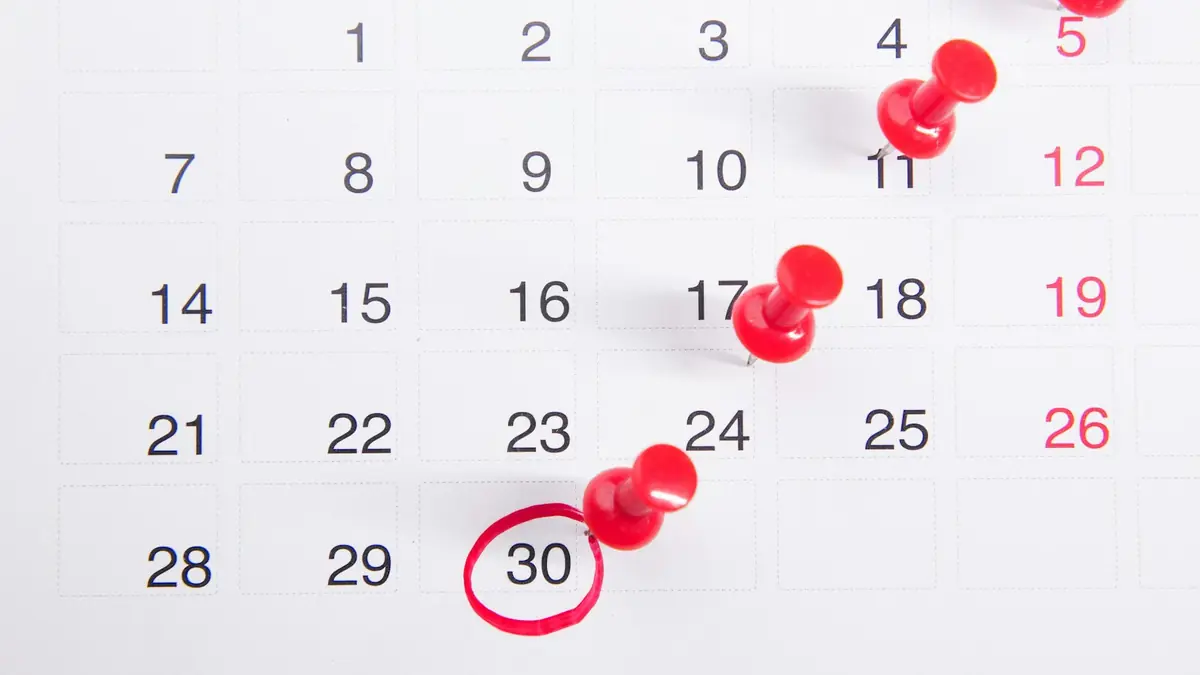 a calendar with red push buttons pinned to it