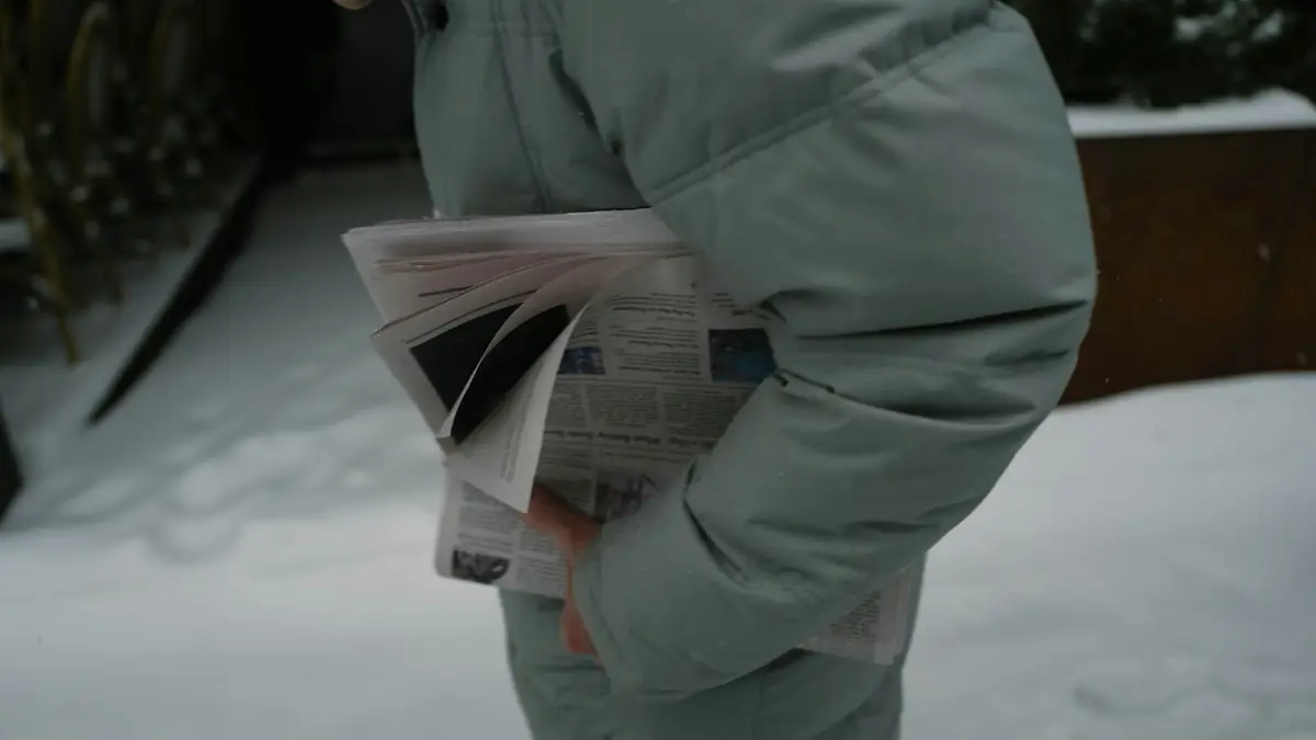 Person holding a newspaper in the snow
