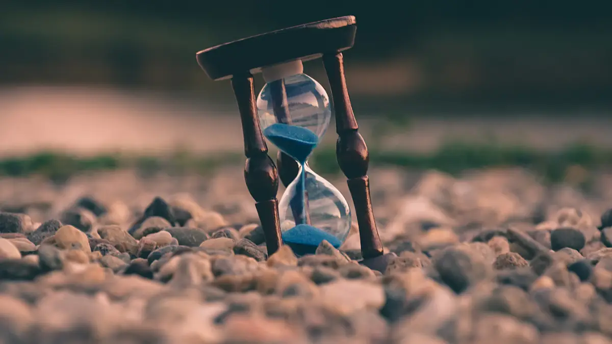selective focus photo of brown and blue hourglass on stones