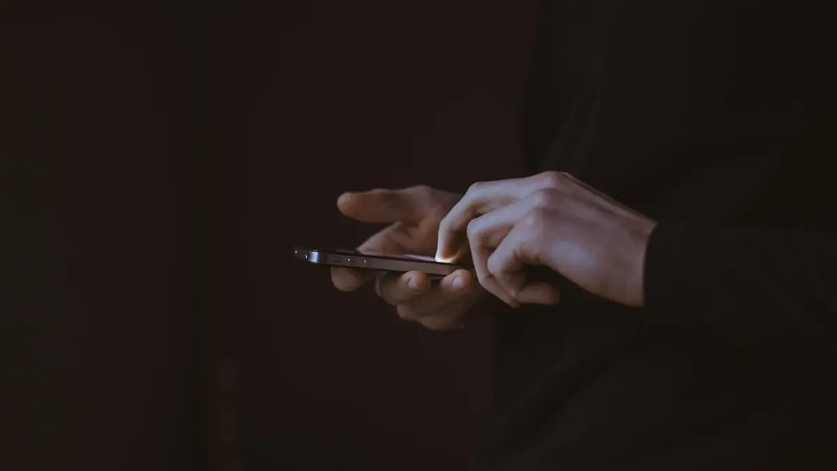 silhouette photo of person holding smartphone
