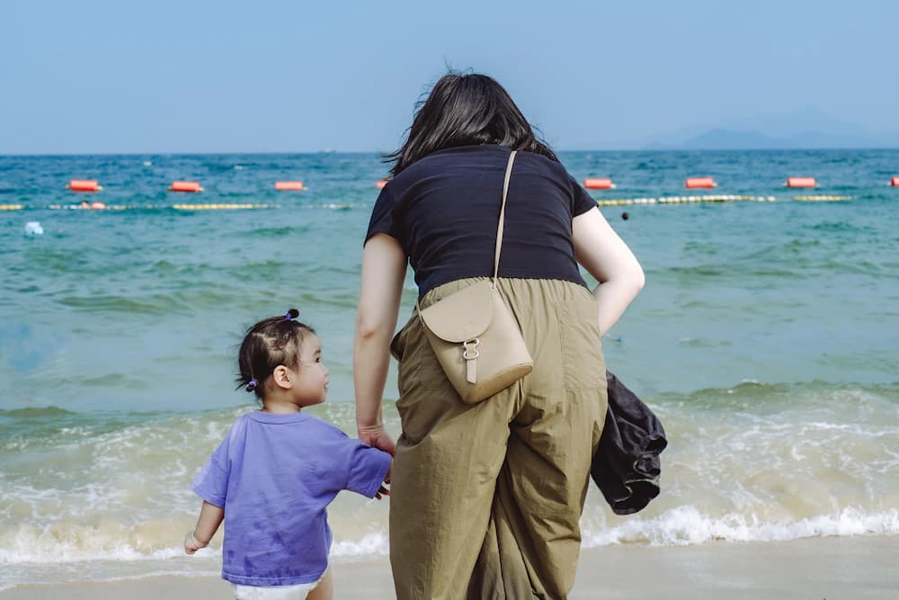 해변에서 손을 잡고 걷는 보호자와 아이
